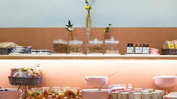 A buffet setup with various food items, including jars of nuts, bowls of fruit, and containers of yogurt.