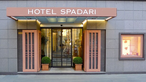 The entrance to Hotel Spadari with a glass door, potted plants, and a signboard. - Hotel Spadari Al Duomo (Milan)