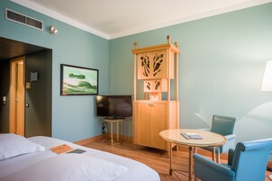 Una camera d'albergo con due letti, una televisione, un armadio, un tavolo e una sedia.