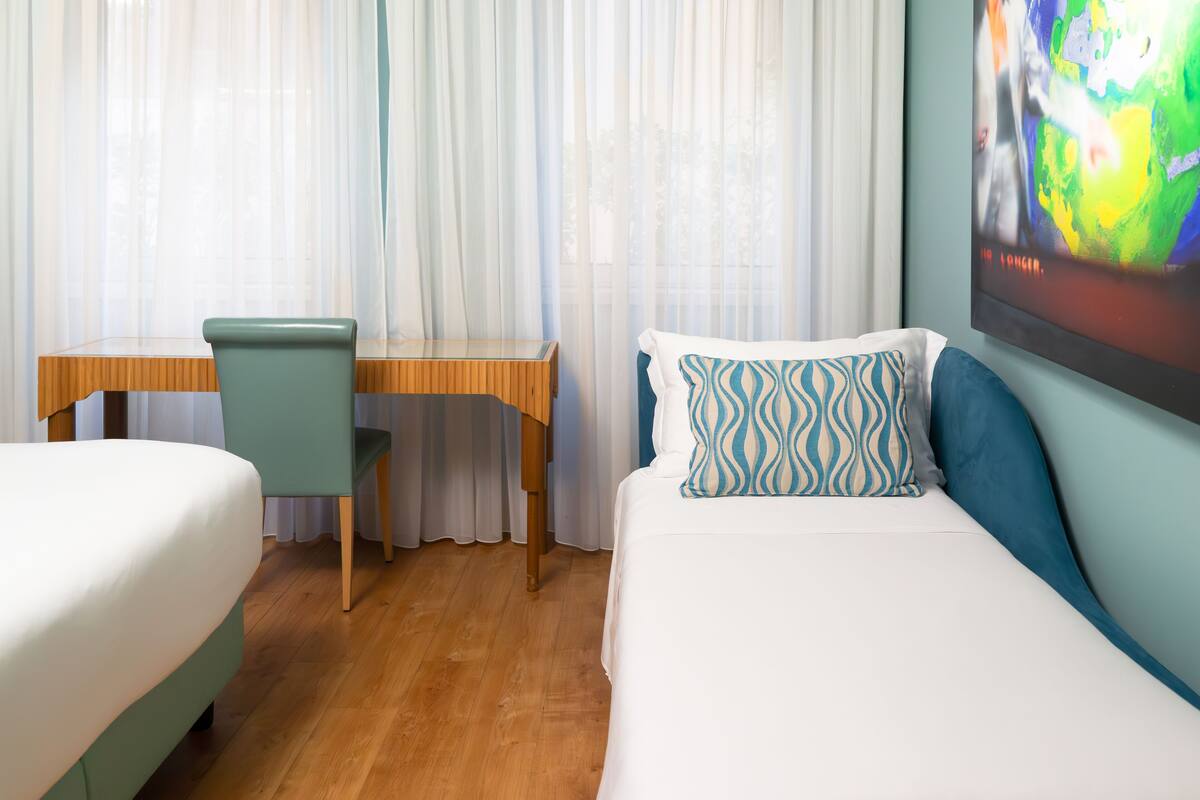A hotel room with a bed, a desk, and a chair.