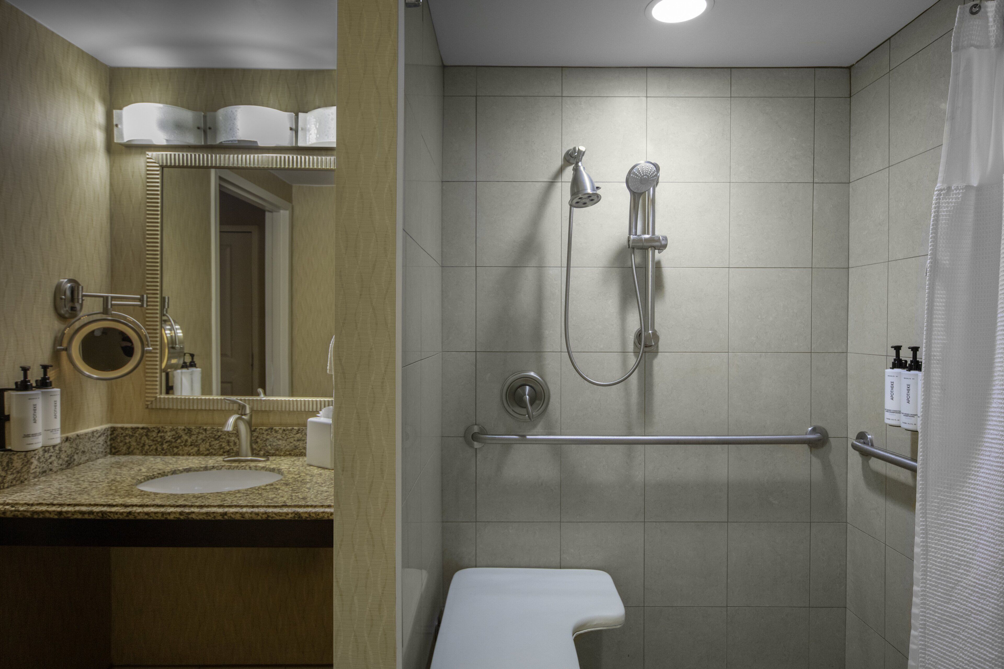 A bathroom with a sink, mirror, and shower.