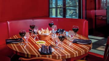 Una mesa de restaurante preparada con copas de vino, una cesta de pan y un plato de comida.