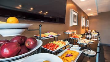 A buffet with various fruits and vegetables, a television, and framed pictures on the wall.