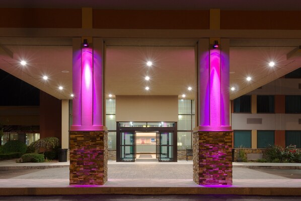 A hotel entrance with a glass door, illuminated pillars, and a paved walkway. - Crowne Plaza Boston - Woburn by IHG (Woburn)