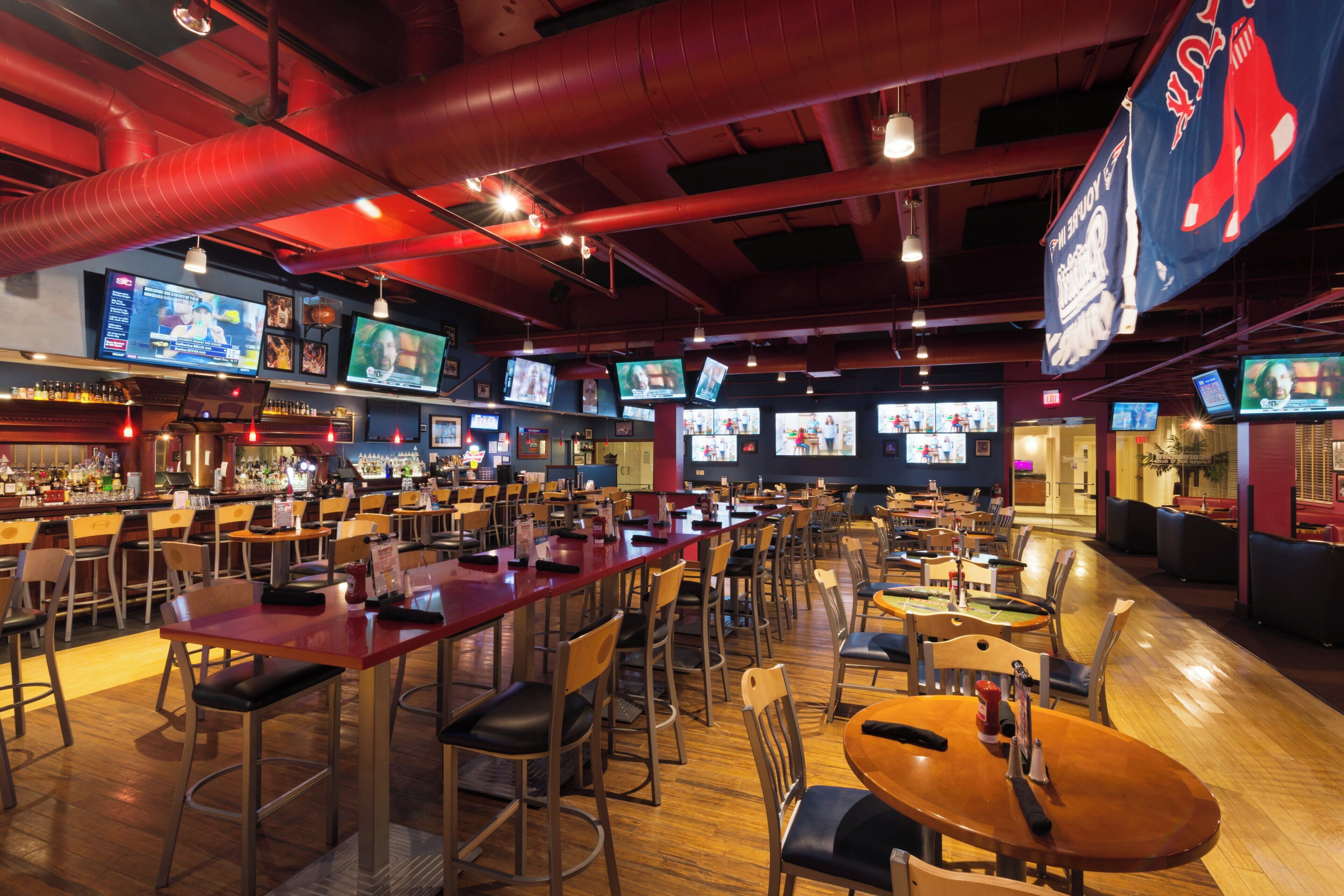 A sports bar with multiple screens, bar area, and seating for patrons.