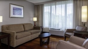 A living room with a sofa, armchairs, a small table, and a standing heater.