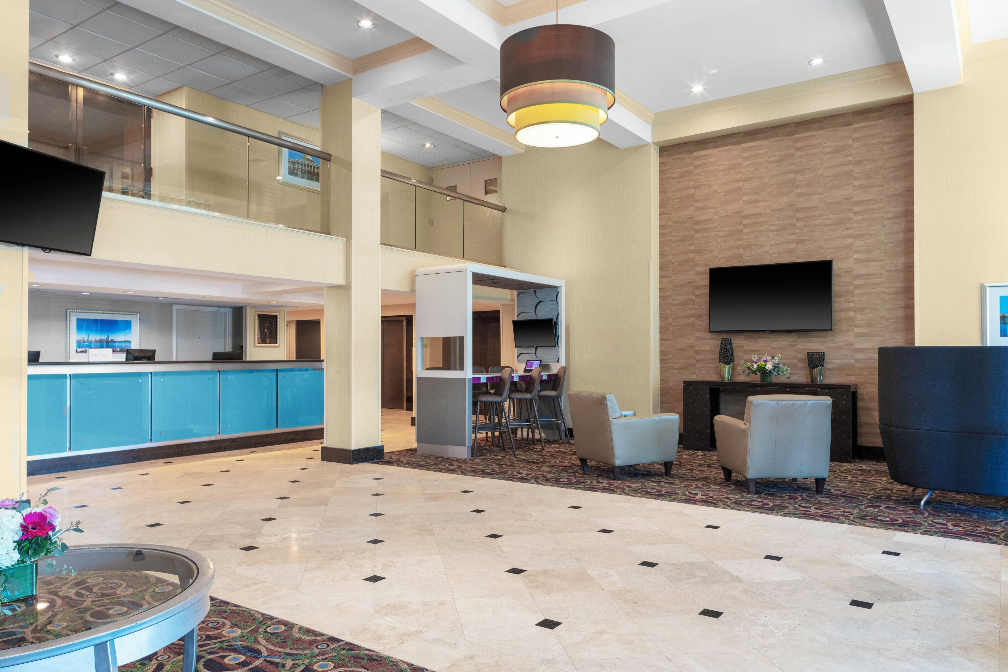 A hotel lobby with a reception desk, seating area, and a large flat-screen TV mounted on the wall.