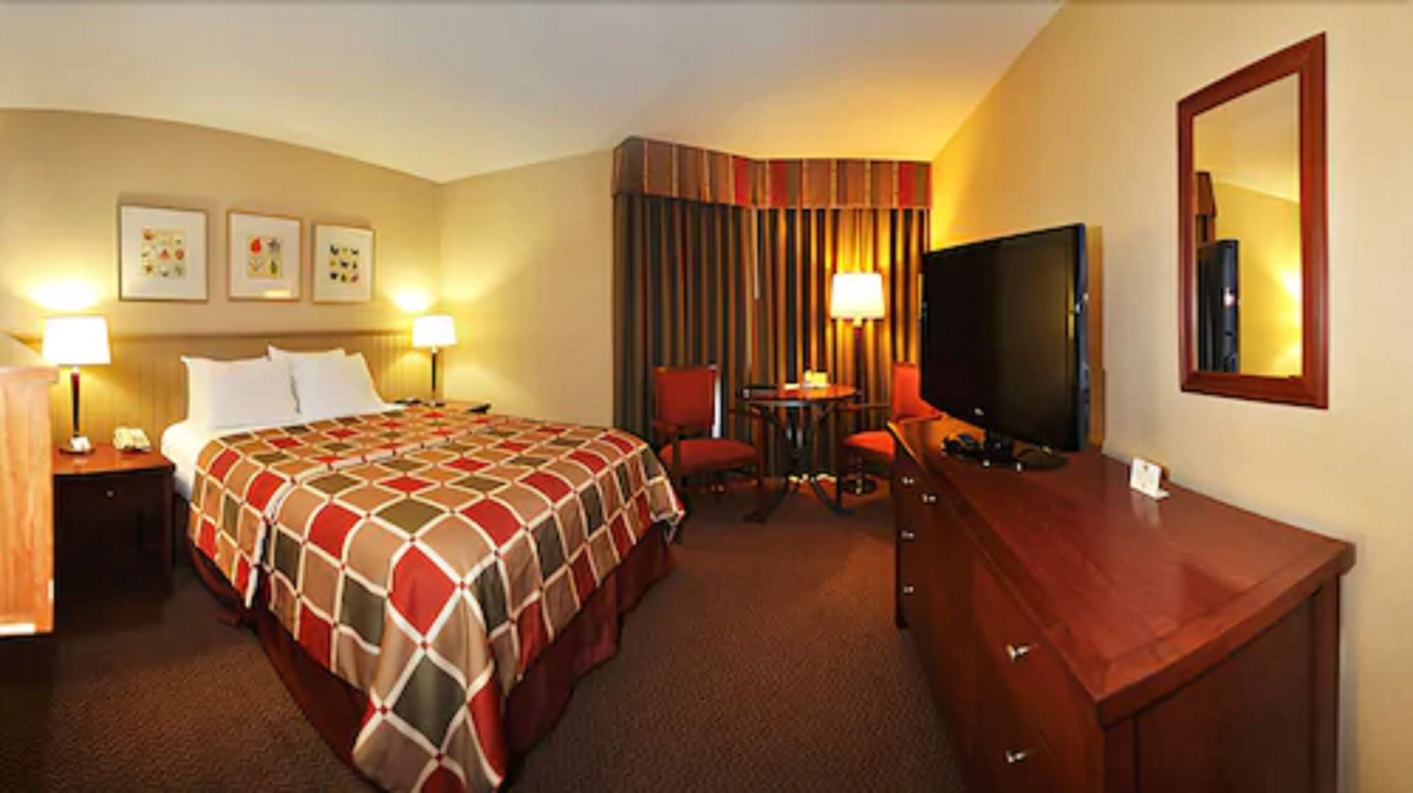 Una habitación de hotel con una cama grande, un escritorio, un televisor y una silla.
