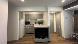 A compact kitchen with white cabinets, a microwave, a sink, and a built-in TV. - Charlottetown Inn & Conference Centre (Charlottetown)