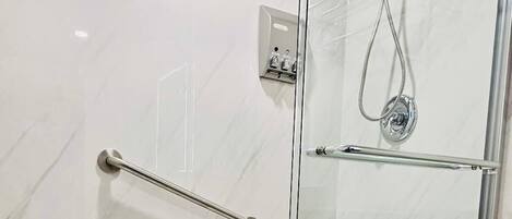 Una ducha con paredes de vidrio, cabezal de ducha de mano y puerta de vidrio.