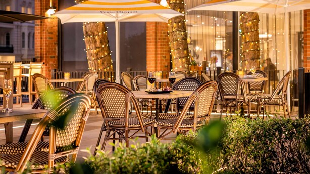 Outdoor seating with wicker chairs and tables, umbrellas, and string lights. - Pullman Auckland Hotel & Apartments (Auckland)