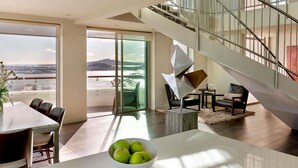 A modern living room with a dining area, a staircase, and a view of a body of water. - Pullman Auckland Hotel & Apartments (Auckland)