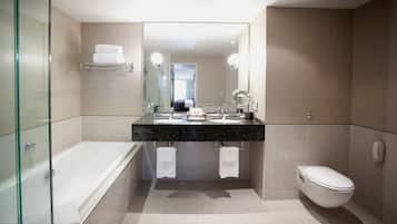 A modern bathroom with a glass-enclosed shower, a double sink vanity, a toilet, and a large mirror.