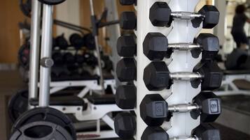 A weightlifting rack with multiple dumbbells and weight plates.