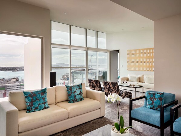 Una sala de estar moderna con un ventanal grande, un sofá, un sillón y una mesa de centro.