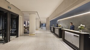 A modern hotel lobby with a reception desk, seating area, and a clear view of the hallway. - Pullman Auckland Hotel & Apartments (Auckland)