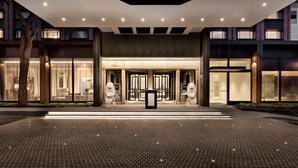 A modern hotel entrance with a brick facade, two lion statues, and a paved entrance area. - Pullman Auckland Hotel & Apartments (Auckland)