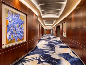 A hotel corridor with a marble-patterned carpet, wooden panel walls, and ceiling lights. - Pullman Auckland Hotel & Apartments (Auckland)