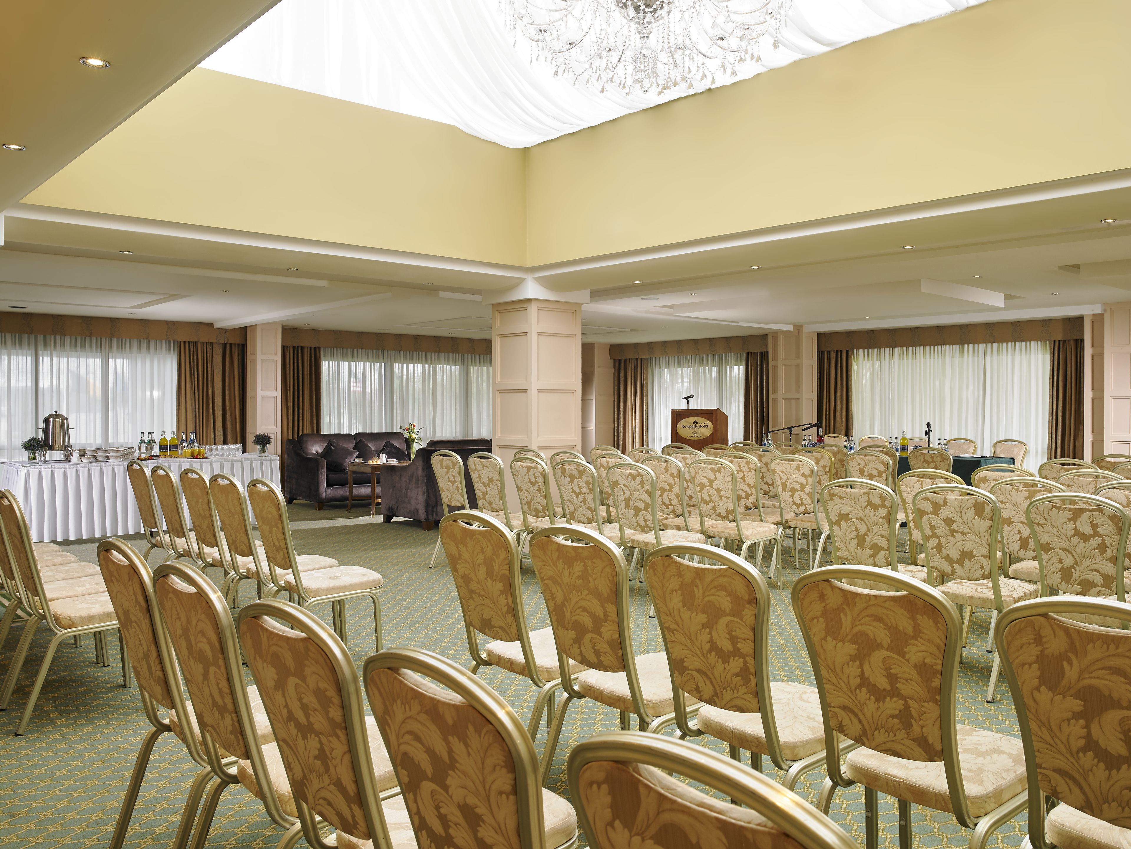 A conference room with rows of chairs, a podium, and a table with refreshments.