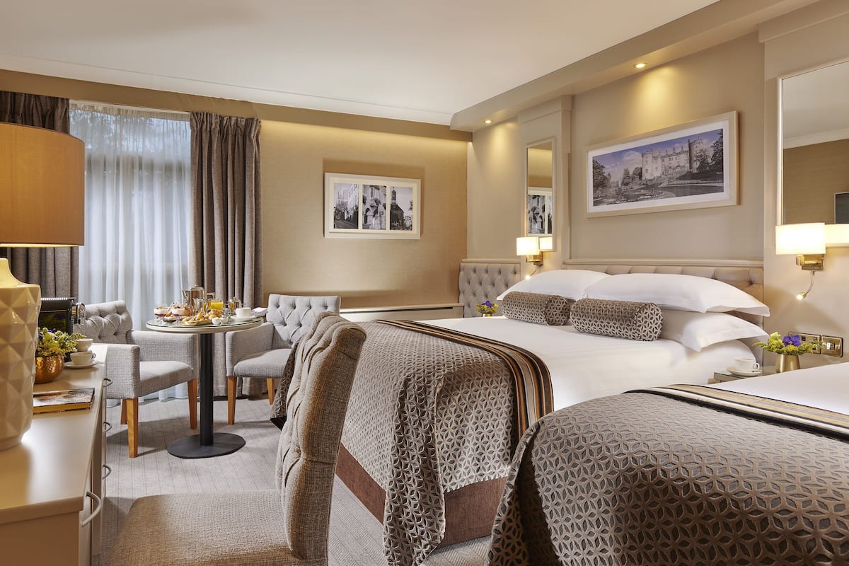 Una habitación de hotel con cama, una mesa de comedor, un sofá y una silla.