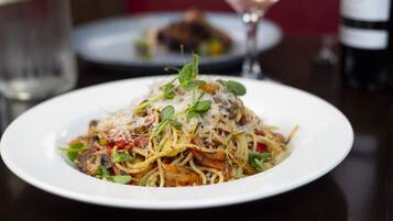 Une assiette de spaghettis avec une sauce tomate, du fromage et des légumes verts.