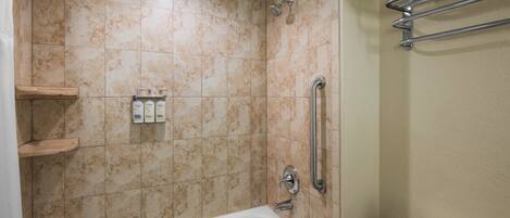 A bathroom with a bathtub, a shower, and a toilet. There are shelves with toiletries and a towel rack.