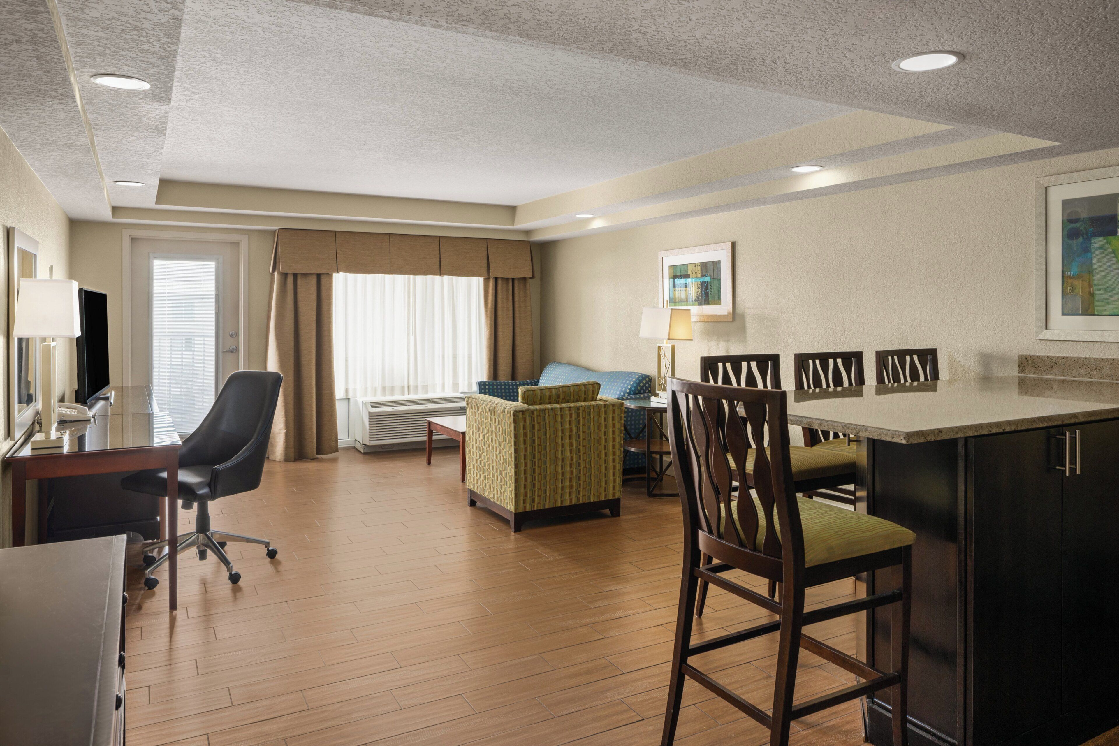 A hotel room with a dining area, a sofa, a TV, and a desk.