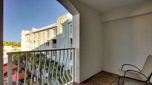 A balcony with a metal railing, a chair, and a view of a building with multiple windows. - Holiday Inn Resort Orlando - Lake Buena Vista by IHG (Orlando)