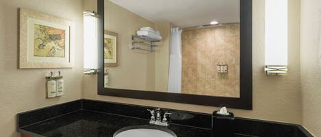A bathroom with a black granite sink, a large mirror, and a framed artwork on the wall.