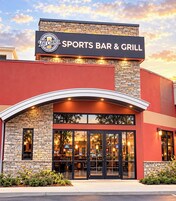 Un bar restaurante deportivo con fachada de piedra y una gran entrada en arco.
