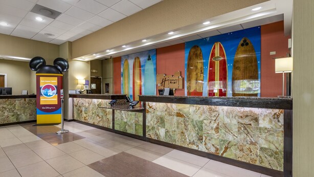 A hotel reception area with a marble counter, a Mickey Mouse decoration, and surfboards on the wall.