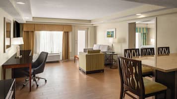 Quarto de hotel com escrivaninha, cadeira, sofá e mesa de jantar.