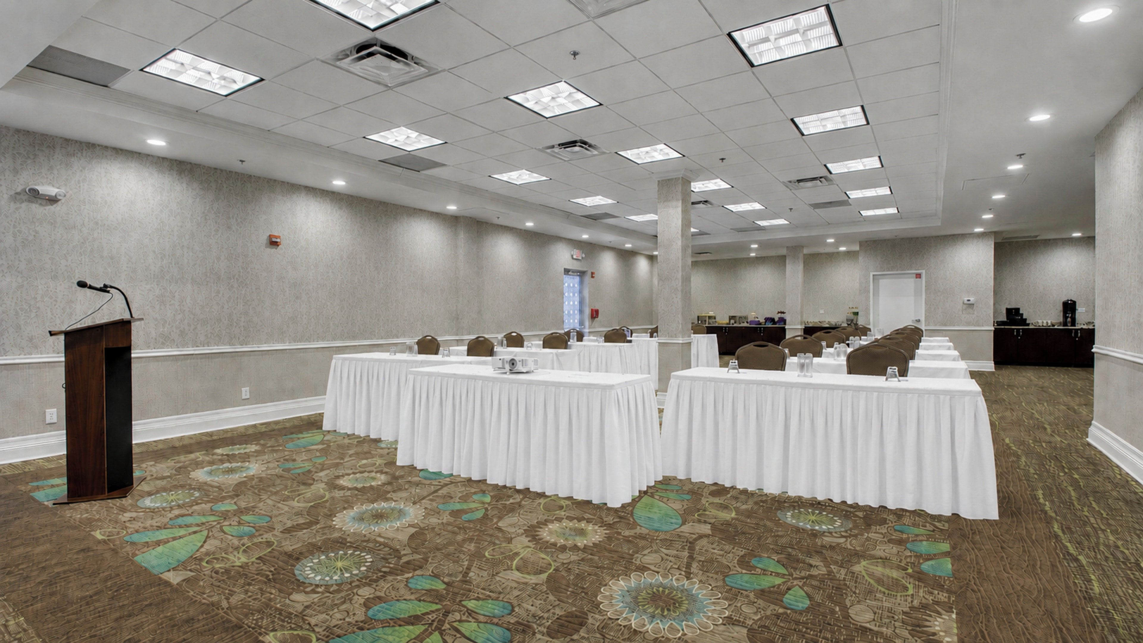 A conference room with a podium, tables, and a patterned carpet.