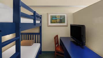 A hotel room with bunk beds, a desk, a chair, a television, and a framed picture on the wall.