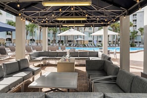 A poolside area with lounge chairs and umbrellas, a fire pit, and a pool. - Holiday Inn Resort Orlando - Lake Buena Vista by IHG (Orlando)