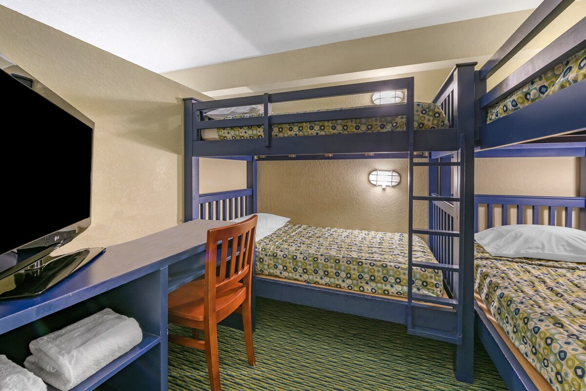 A bunk bed room with a desk, chair, and a television.