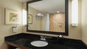 A bathroom with a large mirror, a black granite sink, and a framed artwork on the wall.
