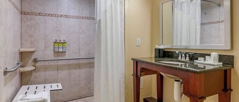 A bathroom with a shower, grab bars, a sink, and a mirror.