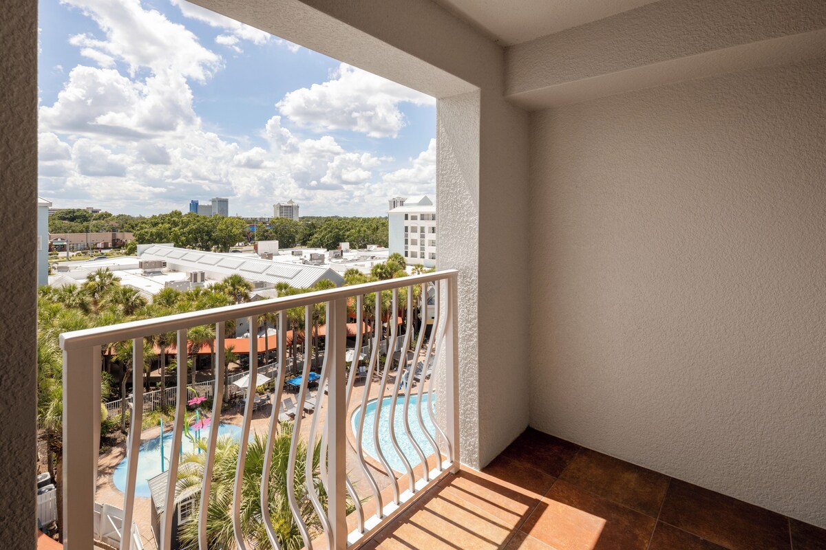 A balcony with a view of a swimming pool and surrounding buildings.