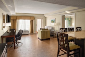A hotel room with a desk, chair, sofa, and dining table. - Holiday Inn Resort Orlando - Lake Buena Vista by IHG (Orlando)
