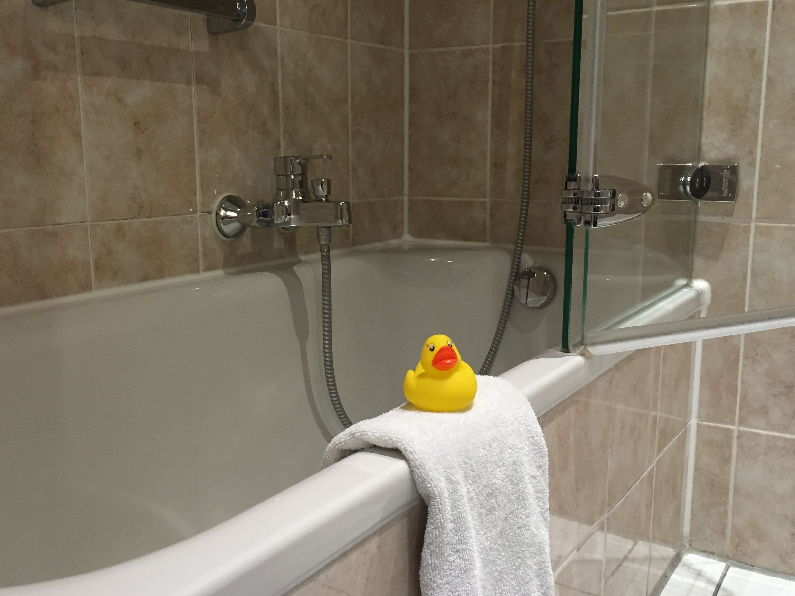 Una bañera con un patito de goma y una toalla.