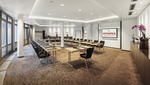 A conference room with a long table, chairs, and a carpeted floor. - Mövenpick Hotel München Airport (Hallbergmoos)