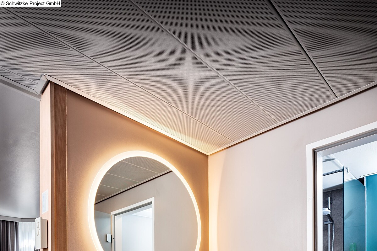 A modern bathroom with a round mirror, a sink, and a shower.