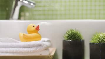 Un baño con una bañera, un patito de goma, una toalla y dos plantas en macetas.
