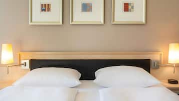 Una habitación de hotel con una cama, dos lámparas de noche y tres cuadros en la pared.