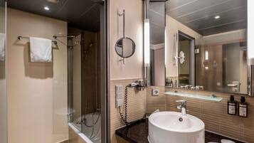 Une salle de bain moderne avec une douche à parois de verre, un grand miroir et un lavabo rond.
