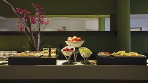 Een buffetopstelling met diverse gerechten en een decoratieve orchidee-arrangement.