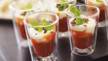 A dessert tray with clear glasses containing layered desserts, garnished with mint leaves and chocolate shavings.