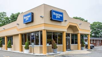 A Rodeway Inn with a beige facade, large windows, and a parking lot.