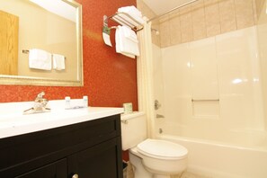 A bathroom with a white sink, mirror, and toilet. There is a towel rack with towels and a shower curtain. - Rodeway Inn Macarthur Airport (Ronkonkoma)
